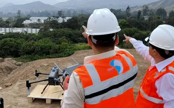 Dos especialistas de Global Mapping con casco y chaleco preparan un vuelo de dron