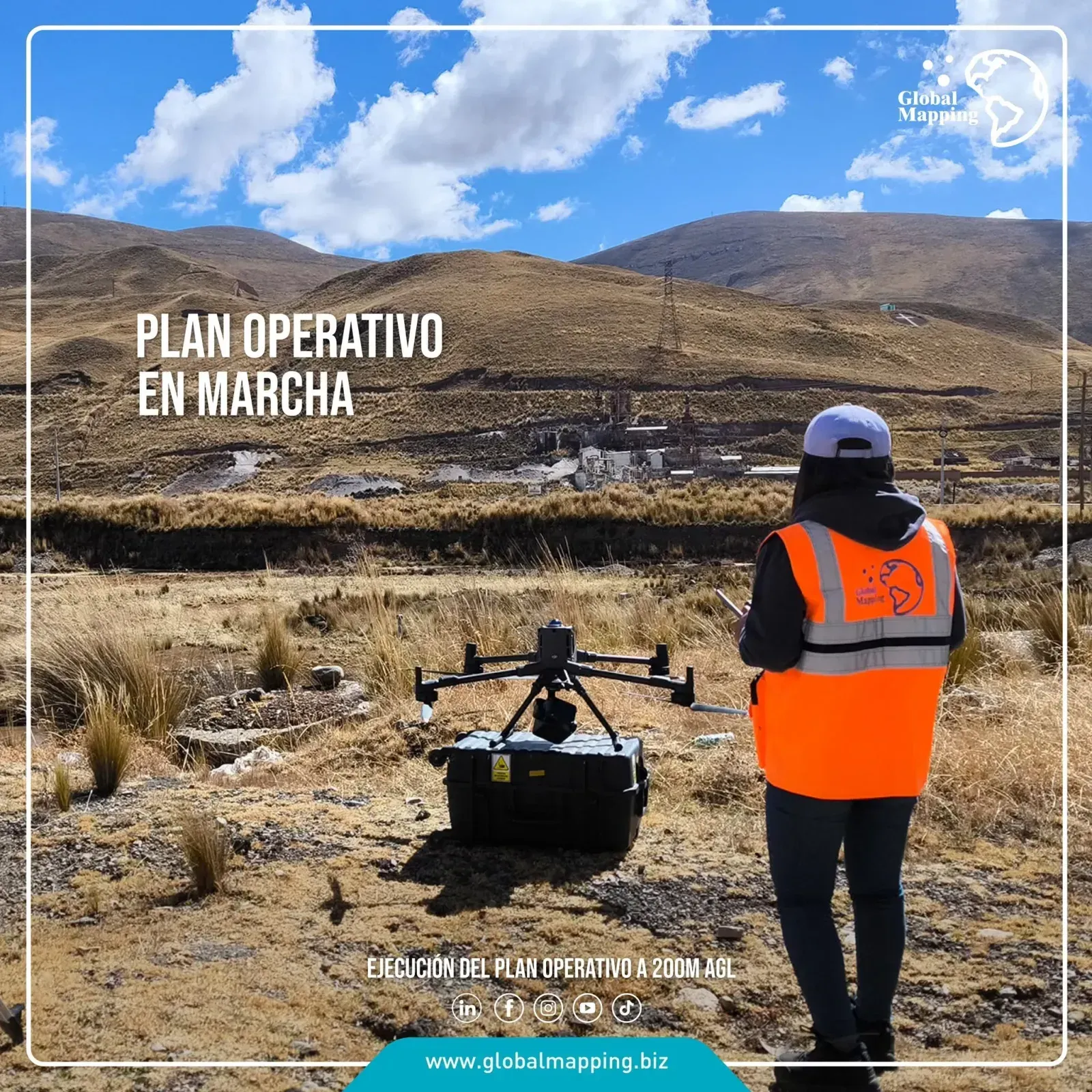 Operadora de espaldas siguiendo el vuelo desde tierra, con el dron sobre su maleta y el complejo industrial al fondo