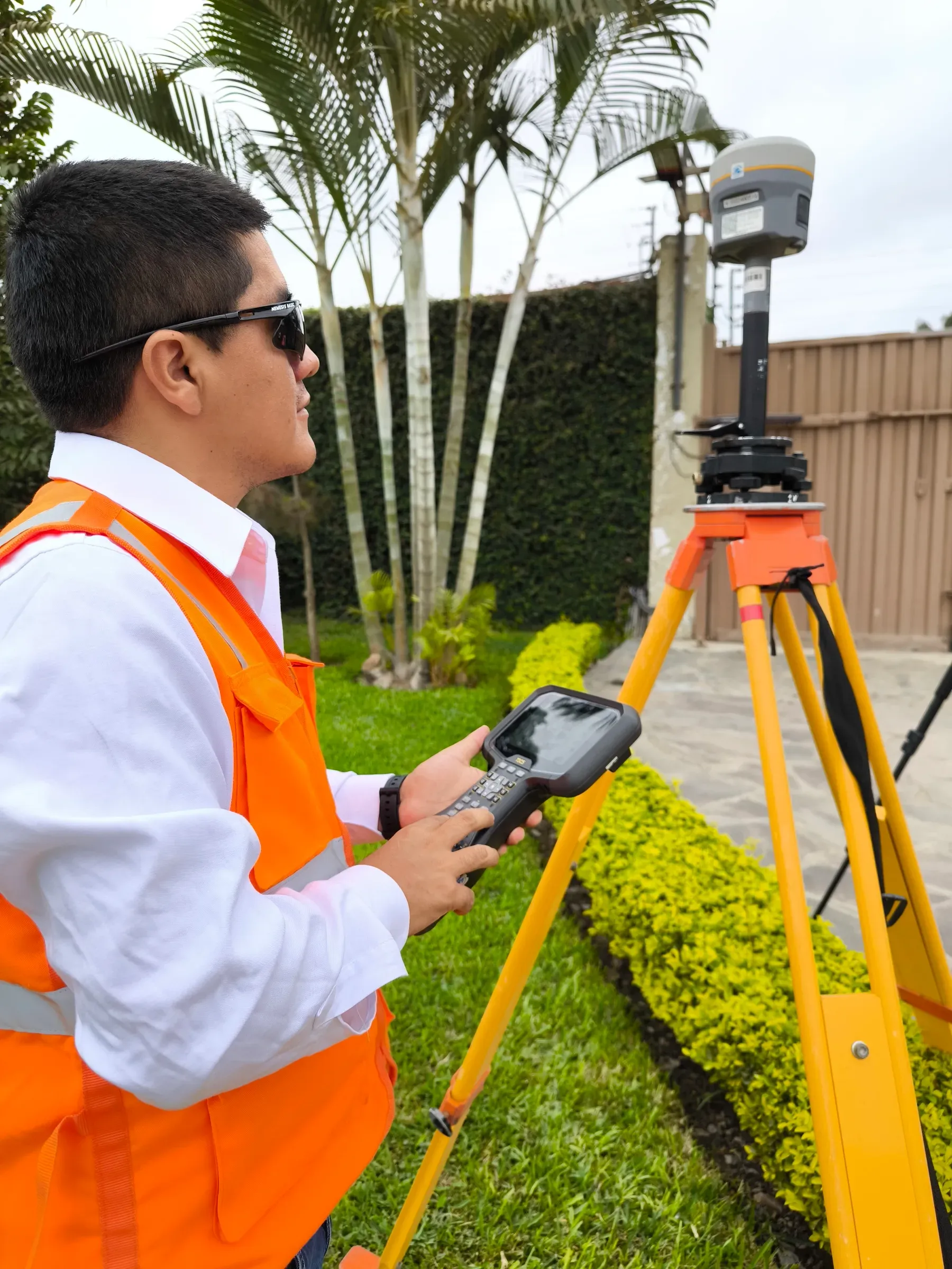 Especialista de Global Mapping con una libreta electrónica en las manos, junto a un receptor GNSS sobre trípode