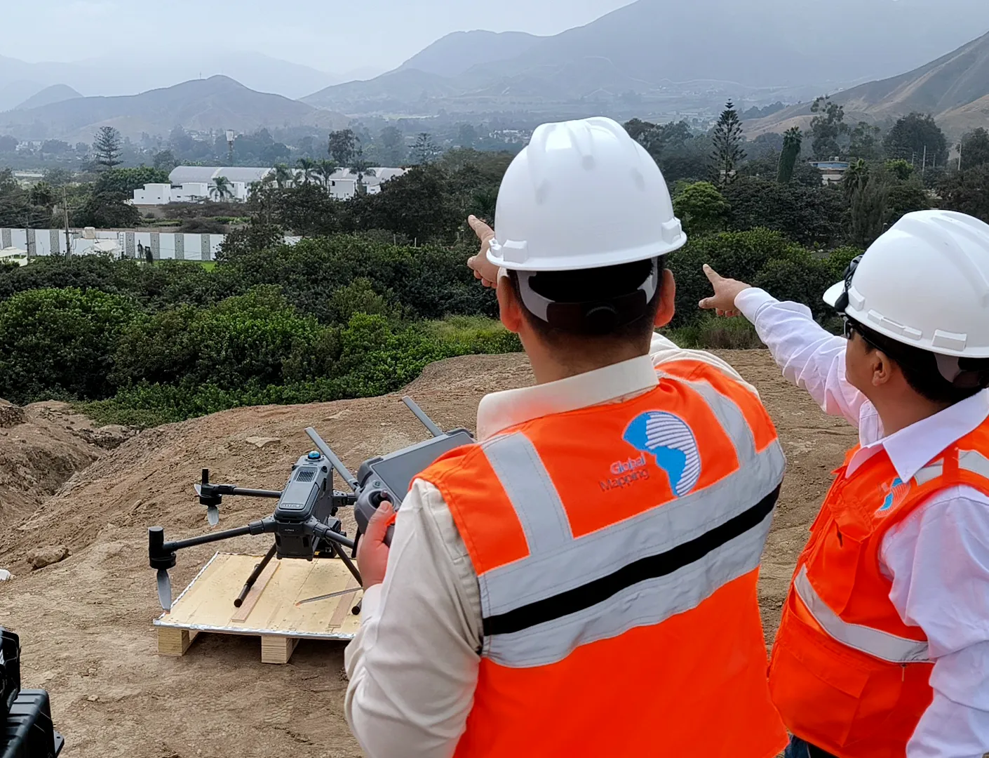 Dos especialistas de Global Mapping operando un dron sobre un valle