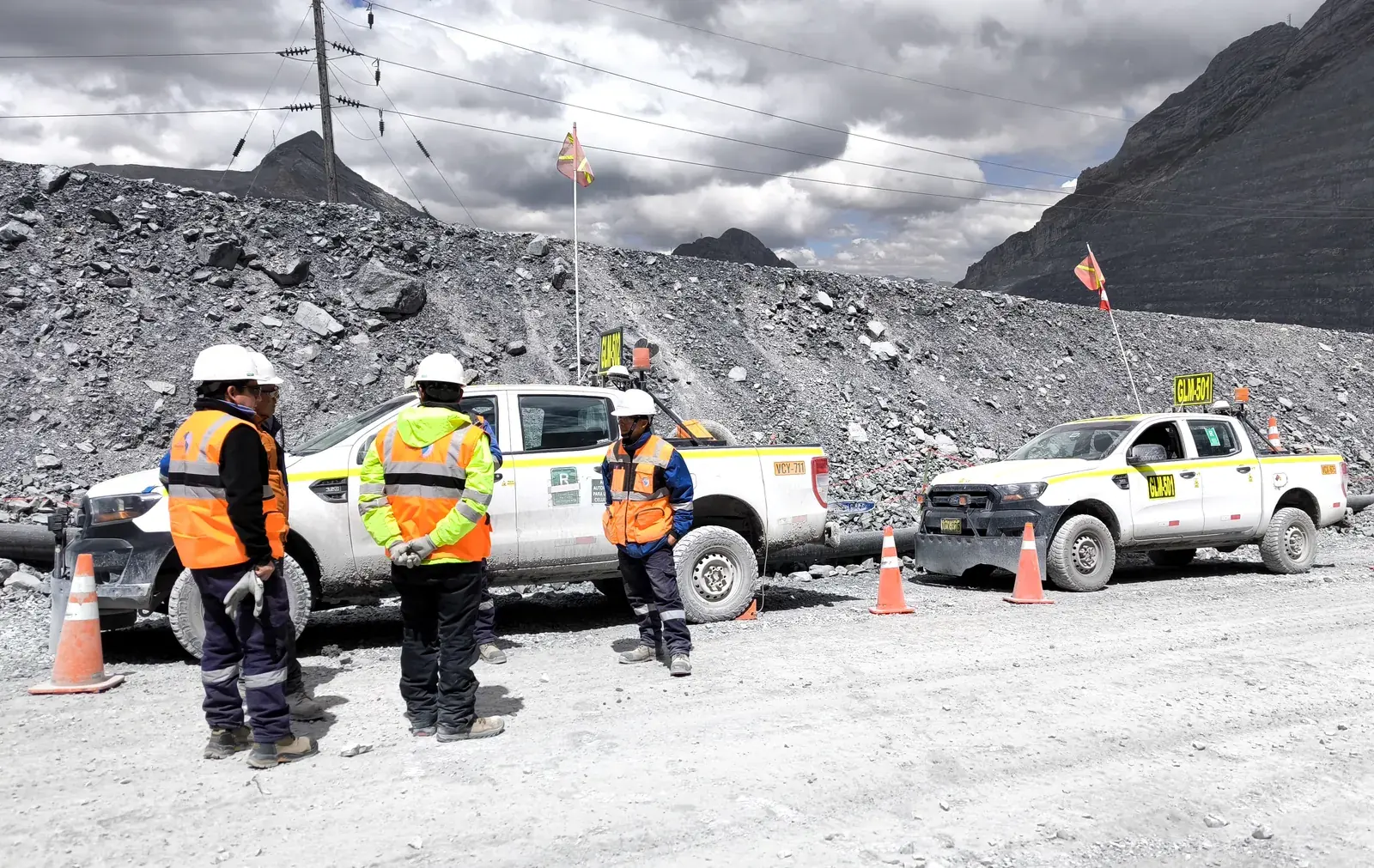 Cuadrilla de topografía junto a camionetas en un tajo de mina a cielo abierto